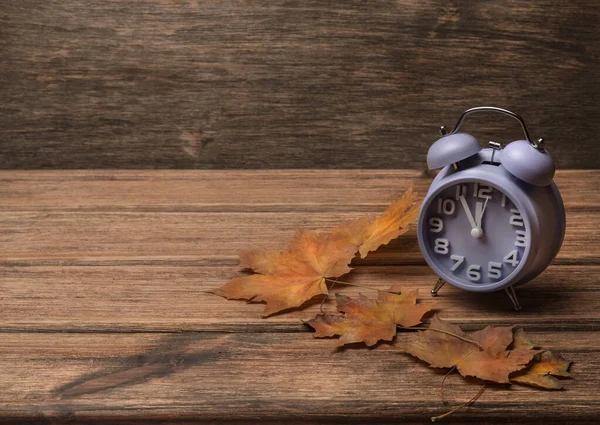 Годинник на старому дерев'яному фоні, прикрашений осіннім листям — стокове фото