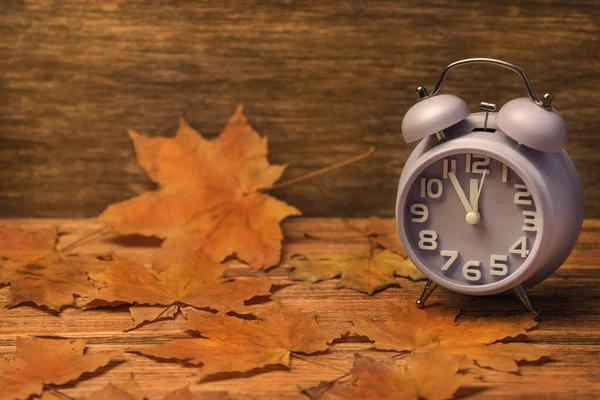 Relógio no fundo de madeira velho decorado com folhas de outono Fotografia De Stock