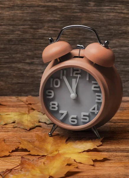 Годинник на старому дерев'яному фоні, прикрашений осіннім листям — стокове фото