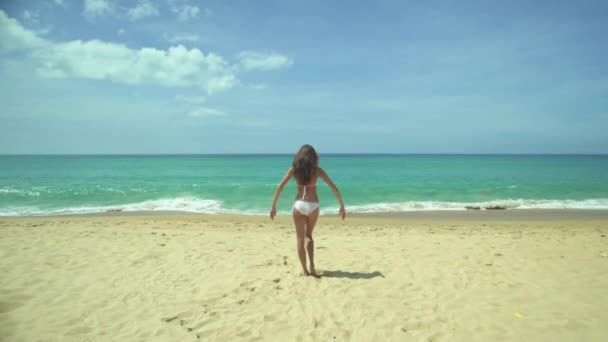 Mujer joven levanta los brazos en la playa — Vídeos de Stock