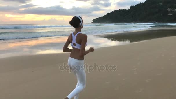 Молодая девушка в спортивном костюме бегает по пляжу — стоковое видео