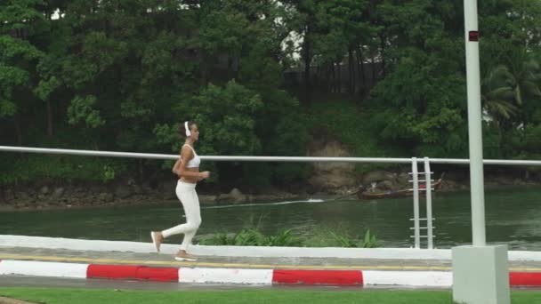 Atletisk kvinna kör på strandpromenaden nära havet — Stockvideo