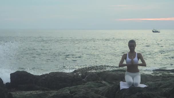 Дівчина займається вправами йоги на морському узбережжі — стокове відео
