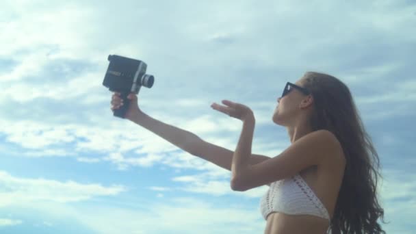 Молодая женщина позирует с ретро-камерой — стоковое видео