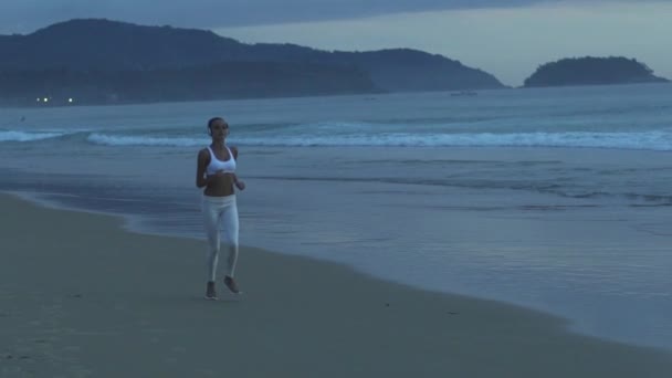 Fitness žena běží za soumraku na tropické pláži — Stock video