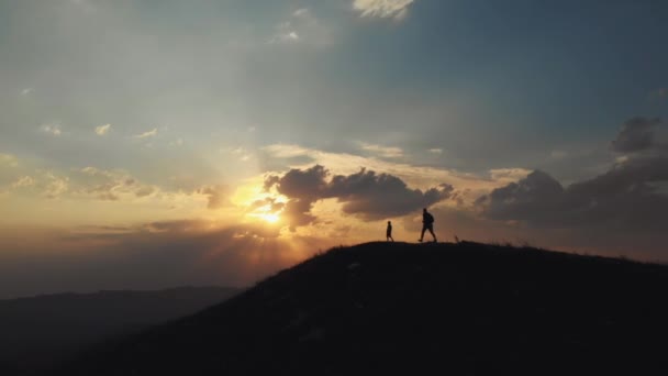 Pai e filho atingindo o topo da colina contra a bela vista do pôr do sol — Vídeo de Stock