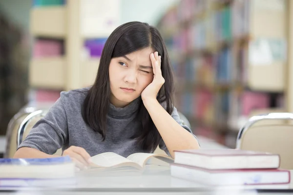 Mulher tem dor de cabeça na biblioteca — Fotografia de Stock
