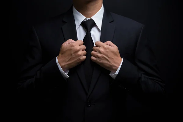 Man in black suit and adjusting his necktie — Stock Photo, Image