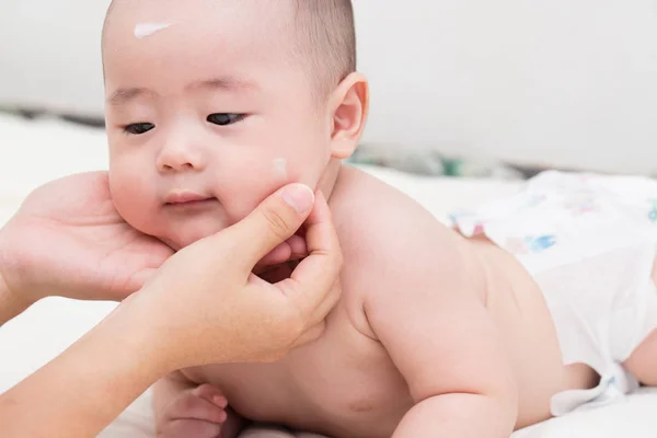 Mère appliquant lotion pour bébé pour fils — Photo