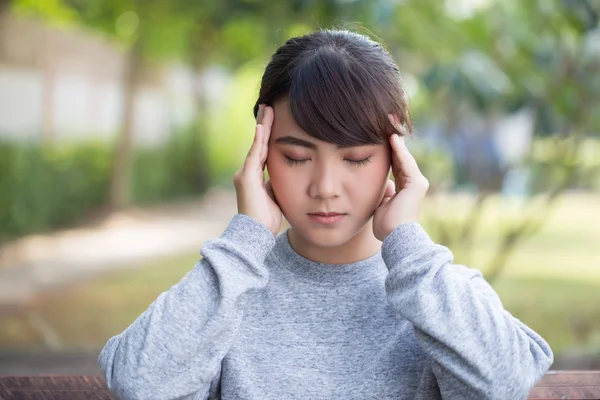 Mujer tiene dolor de cabeza en el parque — Foto de Stock