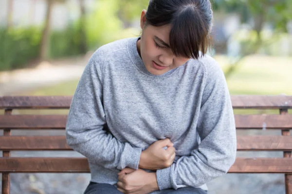 Mujer tiene dolor de estómago en el parque — Foto de Stock