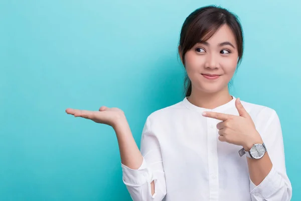 Asiatisk kvinna som pekar till kopia utrymme isolerad på blå backgrou — Stockfoto