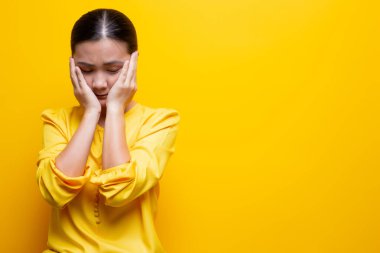 Üzgün kadın sarı arka planda izole edilmiş.