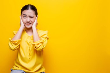 Kadın kulaklarını kapatıyor ve sarı sırtının üzerinde tek başına dikiliyor.