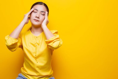 Kadının baş ağrısı sarı arka planda izole edilmiş.