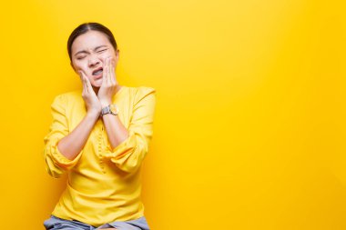 Kadının diş ağrısı sarı arka planda izole edilmiş.