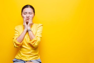 Kadının diş ağrısı sarı arka planda izole edilmiş.