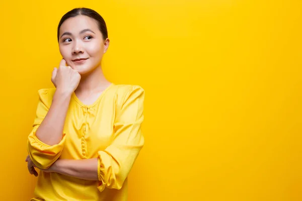 Femme heureuse pensant et se tenant isolée sur fond jaune — Photo