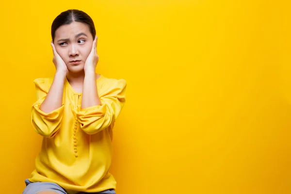 Mujer cubriéndose las orejas y de pie aislada sobre fondo amarillo — Foto de Stock