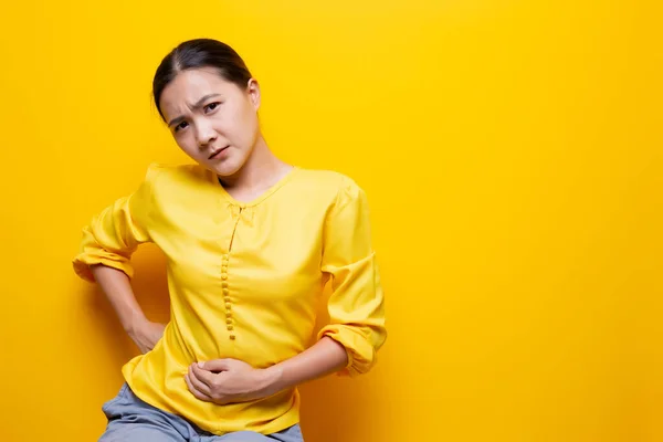 Mujer tiene dolor de estómago aislado sobre fondo amarillo — Foto de Stock
