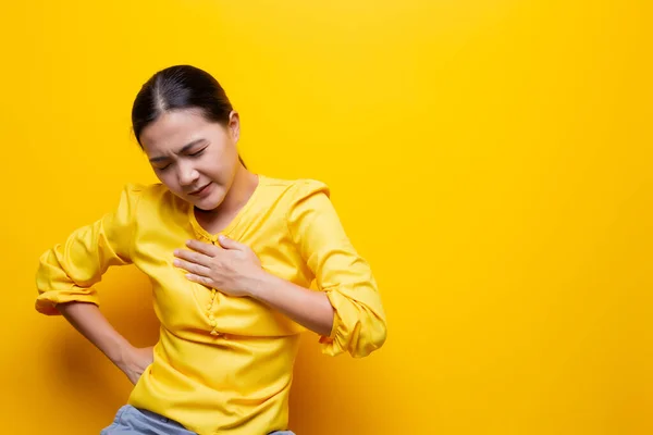 Mujer tiene dolor en el pecho aislado sobre fondo amarillo — Foto de Stock