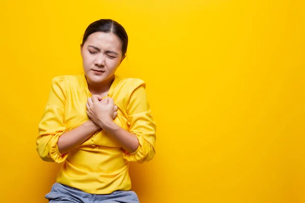 Mulher tem dor no peito isolado sobre fundo amarelo — Fotografia de Stock