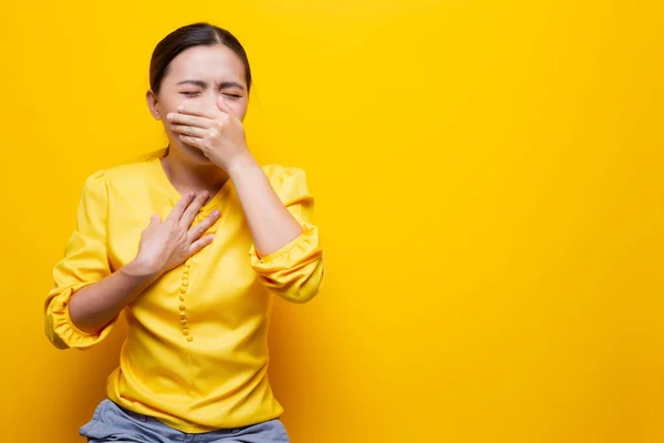 Mujer tiene dolor de garganta aislado sobre fondo amarillo — Foto de Stock