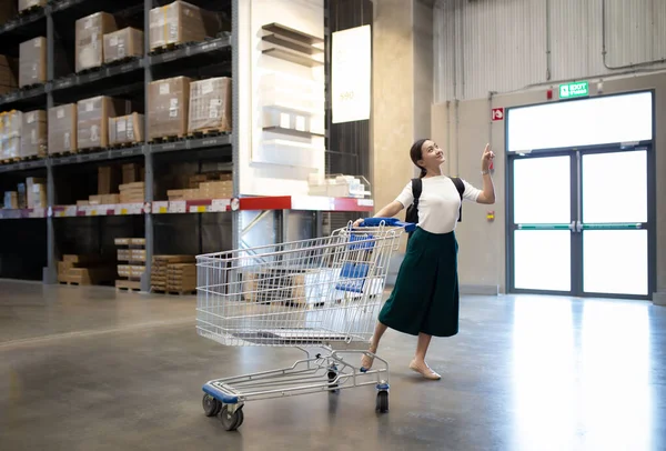 Vrouw gebruik winkelwagentje voor winkelmeubelen in magazijn — Stockfoto