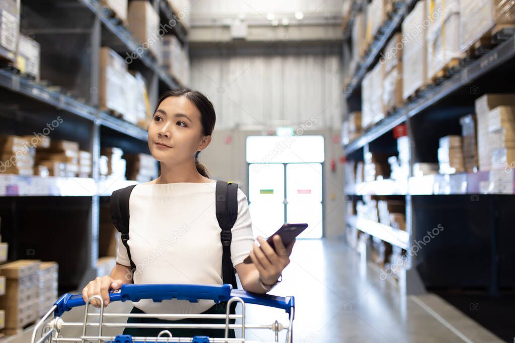 Woman use cart for shopping furniture in warehouse