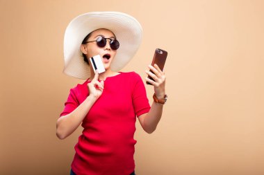 Şapka ve güneş gözlüğü takan kadın akıllı telefon ve kredi kartı kullanıyor.