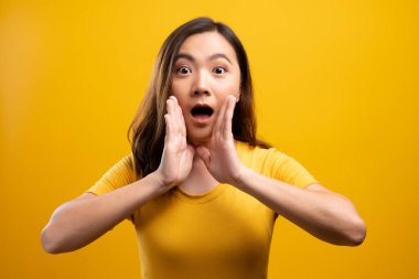 Kadın, sarı arka planda izole edilmiş dedikodu hareketi yapıyor.