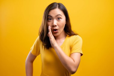 Kadın, sarı arka planda izole edilmiş dedikodu hareketi yapıyor.