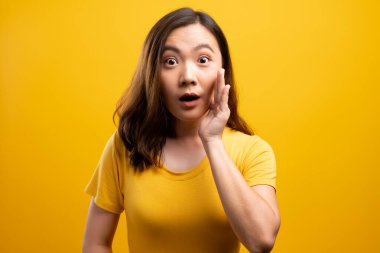 Kadın, sarı arka planda izole edilmiş dedikodu hareketi yapıyor.