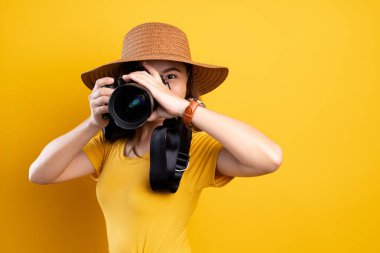 Yel üzerinde fotoğraf makinesiyle duran şapkalı kadın.