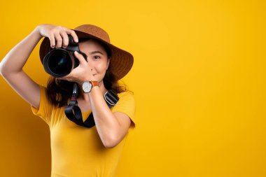 Yel üzerinde fotoğraf makinesiyle duran şapkalı kadın.
