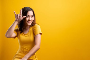 Aşık bir kadın, sarı arka planda izole bir kalp gösteriyor.