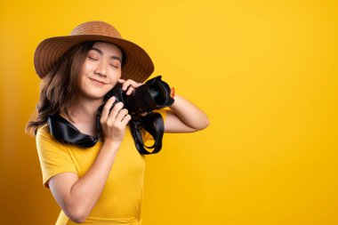 Yel üzerinde fotoğraf makinesiyle duran şapkalı kadın.