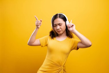 Kulaklıklı bir kadın, izole edilmiş sarı sırtından müzik dinliyor.