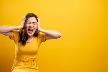 Kızgın kadın sarı arka planda izole bir şekilde çığlık atıyor.