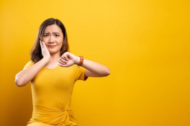 Şok olmuş bir kadın, sarı bir kol saati ile el ele tutuşuyor.