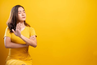 İzole edilmiş sarı arka planda dur işareti yapan kadın