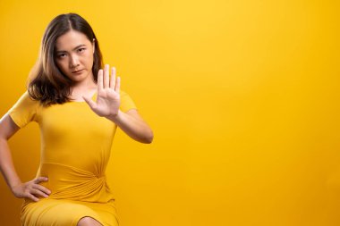 İzole edilmiş sarı arka planda dur işareti yapan kadın