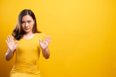 İzole edilmiş sarı arka planda dur işareti yapan kadın