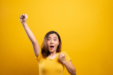 Mutlu kadın sarı arka planda izole edilmiş kazanan bir jest yapar.