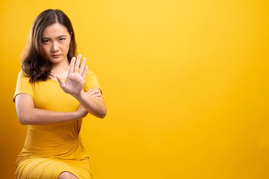 İzole edilmiş sarı arka planda dur işareti yapan kadın