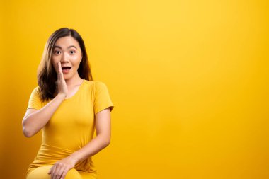 Kadın, sarı arka planda izole edilmiş dedikodu hareketi yapıyor.