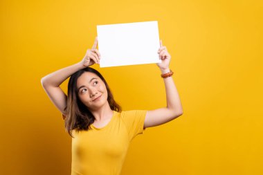 Sarı arkaplan üzerinde kağıt kopyalama alanı gösteren kadın