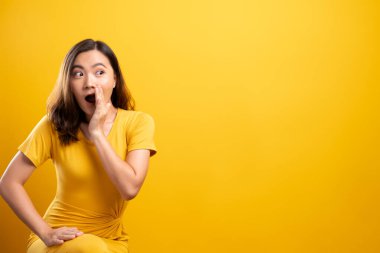 Kadın, sarı arka planda izole edilmiş dedikodu hareketi yapıyor.