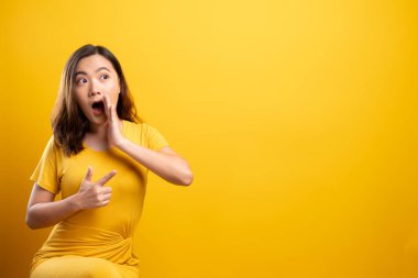 Kadın, sarı arka planda izole edilmiş dedikodu hareketi yapıyor.