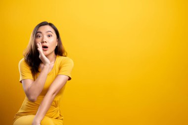 Kadın, sarı arka planda izole edilmiş dedikodu hareketi yapıyor.